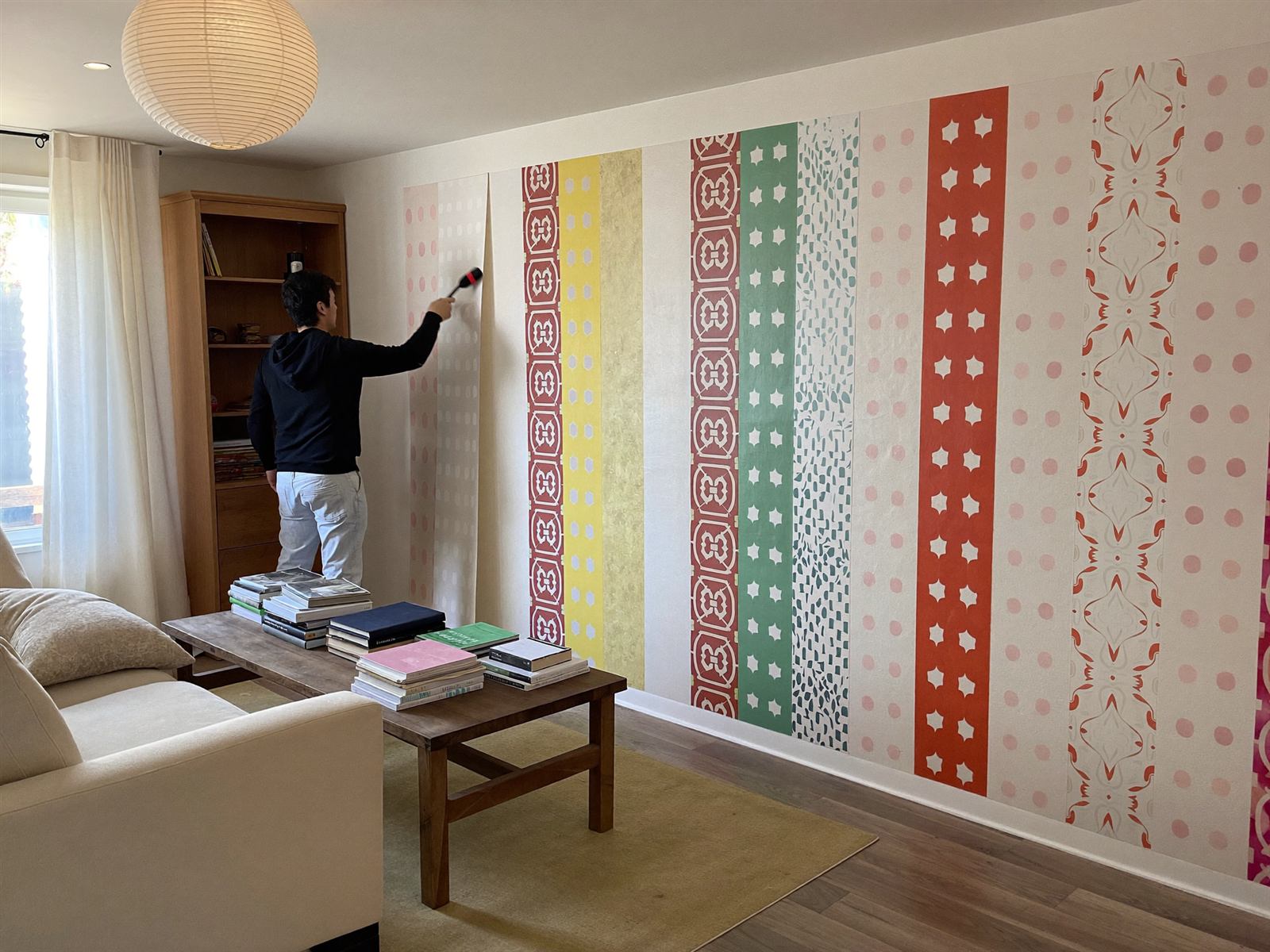 Handwerker tapeziert eine Wohnzimmerwand mit Vliestapete